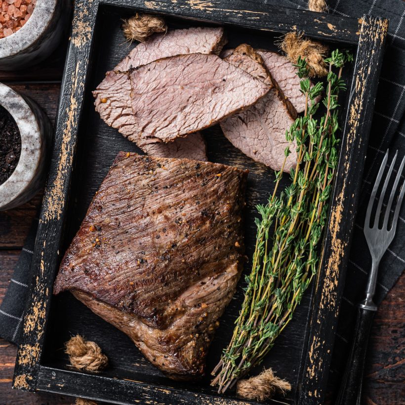 grilled-tri-tip-steak-sirloin-bottom-beef-in-a-tray-with-herbs-wooden-background-top-view.jpg